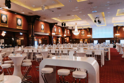 Une salle prête à accueillir un événement : chaque table et chaque chaise est minutieusement positionnées.